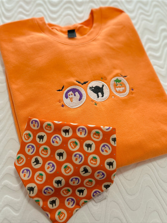 Orange shirt with Halloween-themed designs on a white textured surface